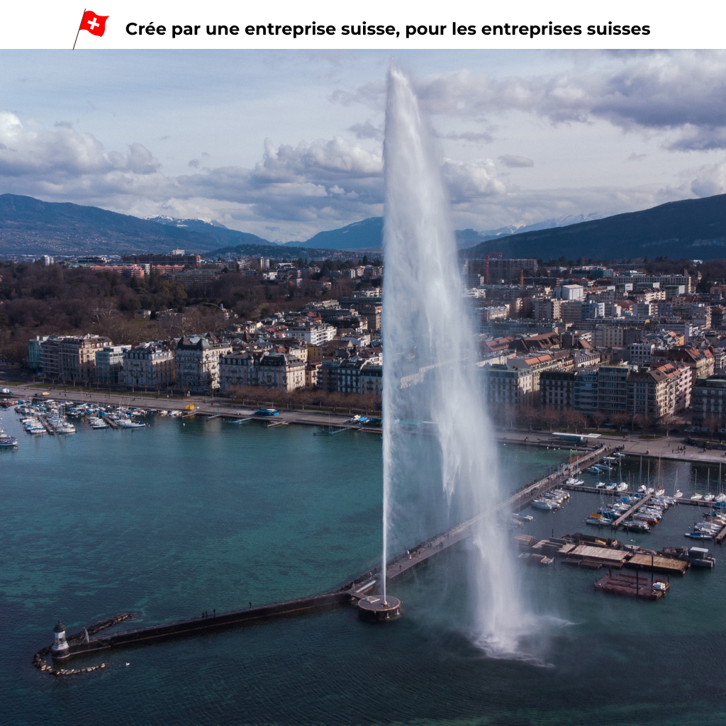 An aerial view of a large water fountain in a lake with surrounding buildings and boats.